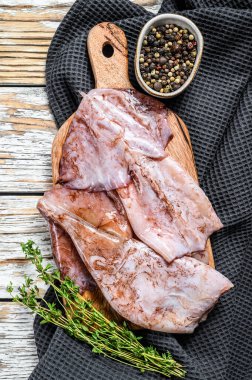 Çiğ mürekkep balığı ve malzemelerin hazırlanması. Beyaz ahşap arka plan. Üst görünüm.