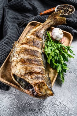 Kesme tahtasında bütün balık mezgit balığı pişirdim. Gri arka plan. Üst görünüm.