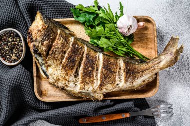 Izgara mezgit balığı pişiriyorum. Gri arka plan. Üst görünüm.