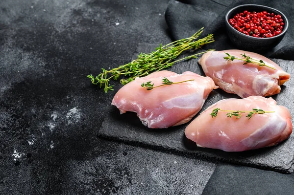 Raw boneless chicken thighs fillet. Black background. Top view. Copy space.