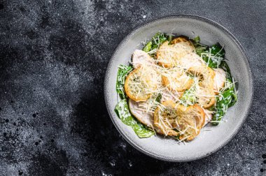 Klasik Sezar salatası ızgara tavuk göğsü, parmesan ve marul. Siyah arka plan. Üst Manzara. Boşluğu kopyala.