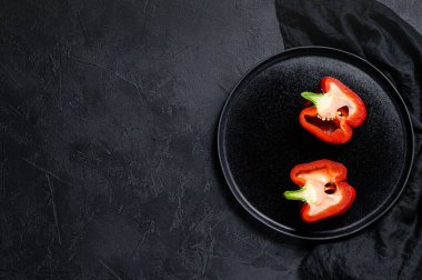 Kırmızı dolmalık biber, iki yarım. Siyah arka plan. Üst Manzara. Metin için boşluk.