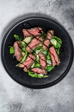 Ispanaklı biftek salatası, roka ve dilimlenmiş biftek. Gri arka plan. Üst görünüm.