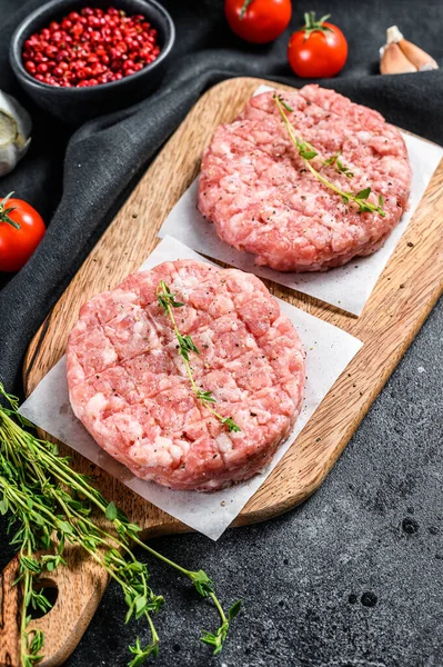 Raw pork cutlets, ground meat patty on a cutting Board. Organic mince. Black background. Top view.