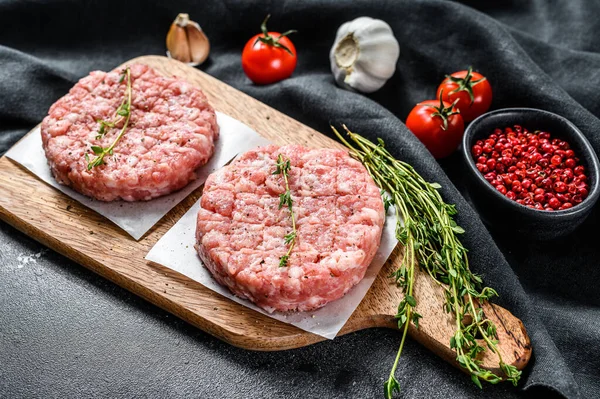 Raw chicken patty, ground meat cutlets on a chopping Board. Organic mince. Black background. Top view.
