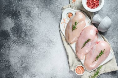 Beyaz kesim tahtasında çiğ tavuk göğsü. Organik çiftlik kuşu. Taze fileto. Gri arka plan. Metin için boşluk