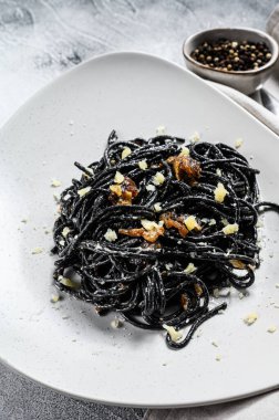 Biber soslu ve parmesanlı siyah spagetti makarna. Gri arka plan. Üst görünüm.