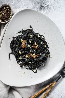 Biber soslu ve parmesanlı siyah spagetti makarna. Gri arka plan. Üst görünüm.