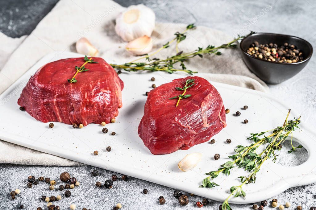 Marble beef tenderloin. Raw filet Mignon steak on a white chopping Board. Gray background. Top view.