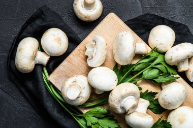 Tahta kesme tahtasında çiğ mantar şampiyonu. Siyah arka plan. Üst görünüm.