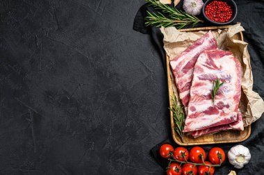 Biberiyeli taze domuz pirzolası ve ahşap bir kasede sarımsak. Siyah arka plan. Üst Manzara. Metin için boşluk.