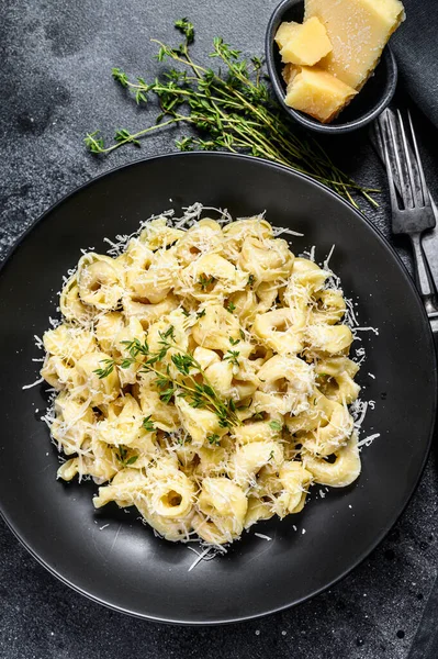 イタリアのトルテリーニパスタとパルメザンチーズ 黒の背景 トップ表示 — ストック写真