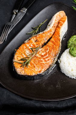 Pirinç ve ıspanakla süslenmiş ızgara biftek. Sağlıklı deniz ürünleri. Siyah arka plan. Üst görünüm.