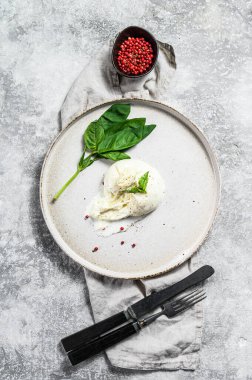 Beyaz tabakta Basil yapraklı Mozzarella Burrata peyniri. Gri arka plan. Üst görünüm.