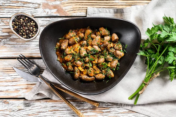 Tavuk ciğeri pişirilmiş kalpleri bir tabakta. Beyaz ahşap arka plan. Üst görünüm.