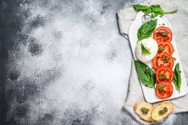 Fesleğen yapraklı ve domatesli Mozzarella burrata salatası. Gri arka plan. Üst Manzara. Metin için boşluk.