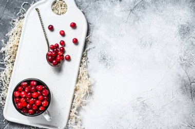 Demir bir kupada olgun kırmızı kızılcıklar. Gri arka plan. Üst Manzara. Metin için boşluk.