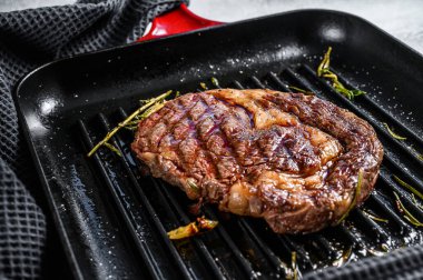 Biberiye ve sarımsaklı ızgara biftek. mermer ibeye eti. gri arka plan. en üstteki görünüm.