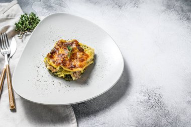 Tabakta ıspanaklı lazanya, vejetaryen yemeği. Beyaz arka plan. Üst Manzara. Boşluğu kopyala.