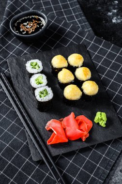 Siyah taşla servis edilen çeşitli suşiler. Siyah arka plan. Üst görünüm.