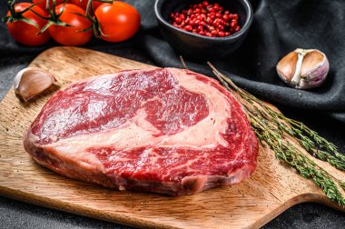 Kesme tahtasındaki mermer biftek. Siyah arka plan. en üstteki görünüm.