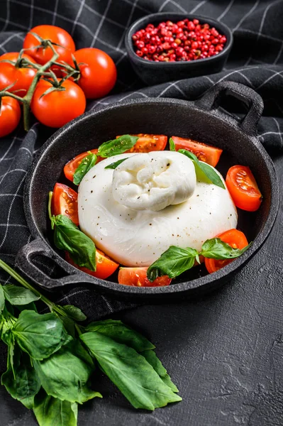 Italian buffalo Burrata cheese with Basil leaves and tomatos. Caprese salad. Black background. Top view.