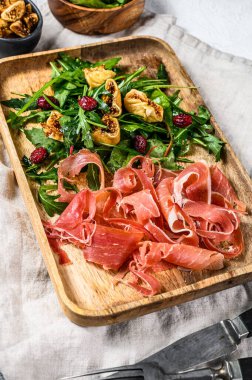 Salad with Serrano jamon, ham, rucola and fig. Antipasto. Gray background, top view clipart