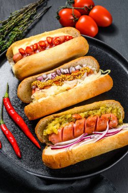 Sosisli sandviçler ve çeşitli malzemeler. Domuz ve sığır etli sosisli nefis sosisler. Siyah arka plan. Üst görünüm.