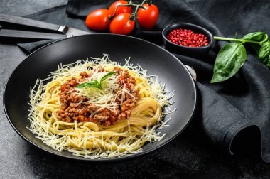 Domatesli spagetti bolonez makarna ve kıyma, parmesan peyniri ve fesleğen. Siyah arka plan. Üst görünüm.