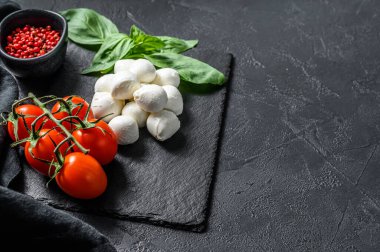Caprese salatası, mini mozzarella peyniri, fesleğen yaprağı ve vişneli domates. Siyah arka plan. Üst Manzara. Boşluğu kopyala.