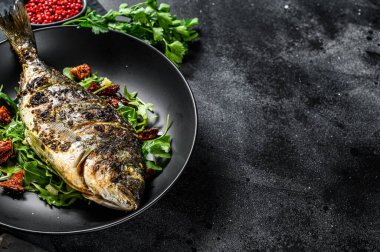 Roka salatası ve domatesli fırında balık. Siyah arka plan. Üst Manzara. Boşluğu kopyala.
