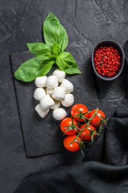 Mini mozzarella peyniri, fesleğen yaprağı ve vişneli domates, Caprese salatası. Siyah arka plan. en üstteki görünüm.