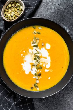 Kremalı balkabağı kreması çorbası ve kabak çekirdeği. Siyah arka plan. Üst görünüm.
