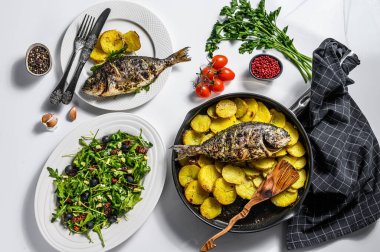 Izgara balık, domatesli roka salatası, fırında patates. Beyaz arka plan. en üstteki görünüm.