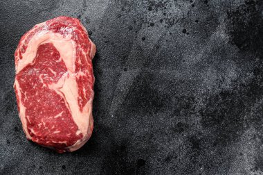 Çiğ biftek pirzolası. Siyah Angus kaburgası. Siyah arka plan. Üst Manzara. Boşluğu kopyala.