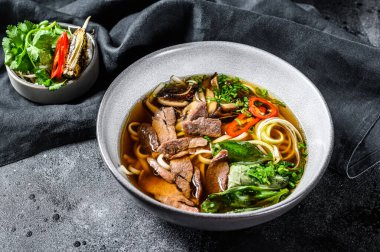 Pho Bo Vietnamlı taze pirinç çorbası sığır eti, otlar ve biberli. Siyah arka plan. Üst görünüm.