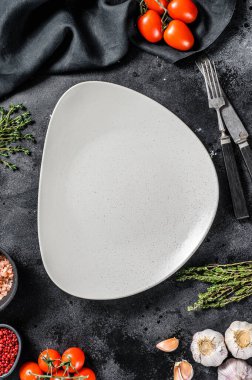 Taze çiğ sebze ve sebzelerin ortasında beyaz boş bir tabak. Sağlıklı, temiz yemek, vejetaryen, diyet yemek konsepti. Siyah arka plan. Üst Manzara. Boşluğu kopyala.