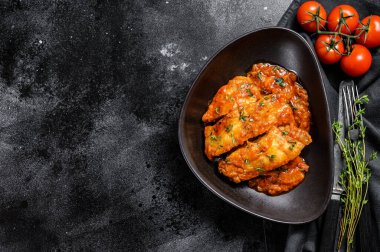 Domates soslu fırında halibut balığı. Siyah arka plan. Üst Manzara. Boşluğu kopyala.