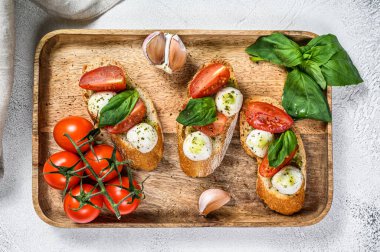 Domatesli sandviç, mozarella peyniri ve fesleğen. İtalyan aperatifi, antipasto. gri arka plan. en üstteki görünüm.
