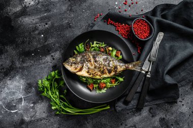 Kızarmış Dorado balığı, roka salatası ve domates. Siyah arka plan. en üstteki görünüm.