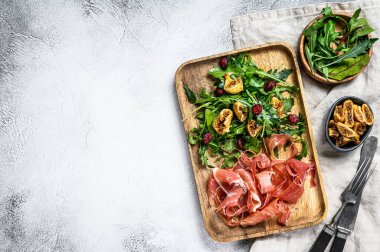 Parmalı salata, jambon, roka ve incir. İtalyan pastası. Gri arkaplan, üst görünüm, metin için boşluk.