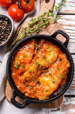 Tavada domatesle pişirilmiş Tilapia balığı. Beyaz ahşap arka plan. Üst görünüm.