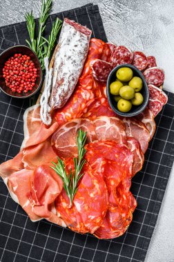 Geleneksel İspanyol mezelerinden yapılmış bir tabak et. Chorizo, Jamon Serrano, Lomo ve Fuet. Gri arka plan. Üst görünüm.