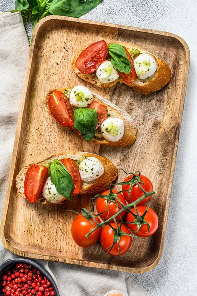 Domates, mozzarella peyniri ve fesleğen. İtalyan aperatifi ya da aperatifi, antipasto. gri arka plan. en üstteki görünüm.