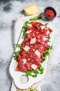 Mermer etli Carpaccio. Çiğ et, siyah Angus. Gri arka plan. Üst görünüm.