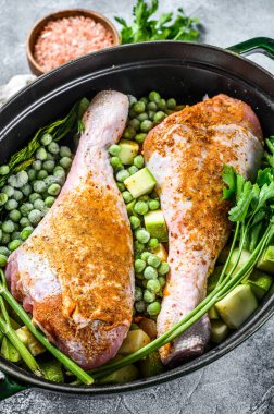 Tavuk yahnisi. Maydanozlu, bezelyeli, kerevizli ve patatesli but tarifi. Gri arka plan. Üst görünüm.