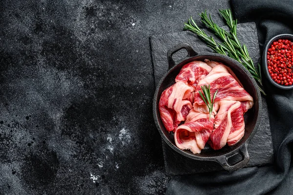 Raw beef bacon, marbled meat. Black background. Top view. Copy space.