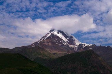 Kazbek. Zirve. Georgia 'nın en yüksek noktası. Gökyüzüne karşı bulutlu yüksek dağ.