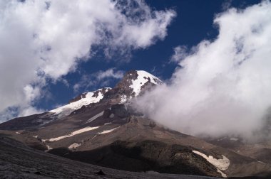 Kazbek. Zirve. Georgia 'nın en yüksek noktası. Gökyüzüne karşı bulutlu yüksek dağ.
