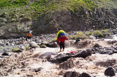 Stepantsminda, Kazbegi bölgesi / Gürcistan - 15 Nisan 2017: Dağlardaki insanlar. Gezginler. Bir dağ nehrinden geçmek.